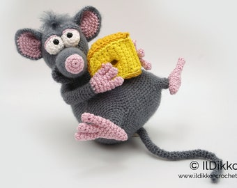 May include: A gray crocheted mouse holding a yellow crocheted block of cheese. The mouse has pink ears, a pink nose, and large white eyes. The mouse's tail is long and gray.
