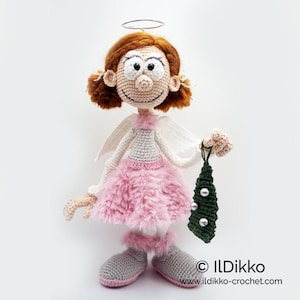 May include: A crocheted doll with auburn hair, a silver halo, and white wings. The doll wears a light pink fuzzy skirt, matching leg warmers, and grey shoes. It holds a small, dark green triangular ornament with three silver beads. Text: ILDikko www.ildikko-crochet.com