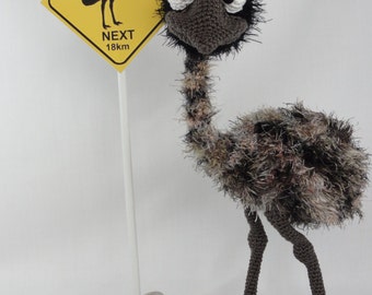 May include: A crocheted emu toy with large googly eyes and a sign that reads "EMUS NEXT 18km".