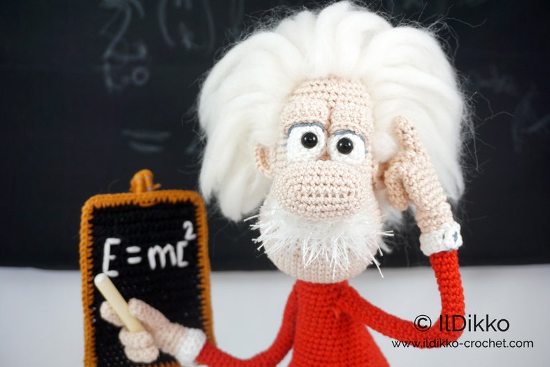Puede incluir: Mu&ntilde;eco de ganchillo hecho a mano de Albert Einstein, con pelo blanco y un su&eacute;ter rojo. El mu&ntilde;eco sostiene una peque&ntilde;a pizarra con la ecuaci&oacute;n E=mc&sup2;. Un art&iacute;culo &uacute;nico y hecho a mano.
