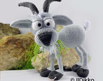 May include: A crocheted goat toy in light gray with dark gray horns and hooves. It features large white eyes with black pupils, a dark gray nose, and a tuft of white hair on its head. The goat is chewing on strands of bright green yarn.