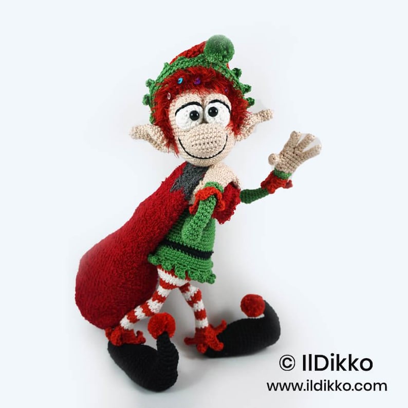 May include: A crocheted elf doll with red hair, a green tunic, and red and white striped leggings. The elf wears a green hat with a red pom-pom and carries a large red sack over one shoulder. The text "&copy; IlDikko www.ildikko.com" is visible.