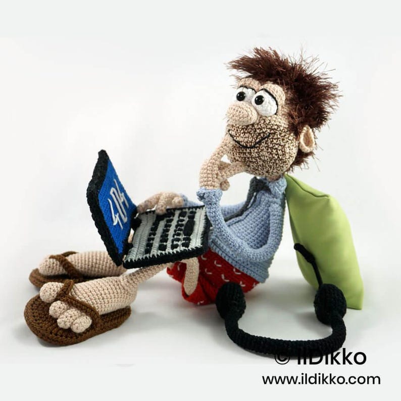 May include: A crocheted figurine of a person with brown hair, wearing a light blue shirt and red patterned shorts, sitting while using a black laptop with a blue screen displaying the text 404. The figure wears brown flip-flops and leans against a lime green pillow.