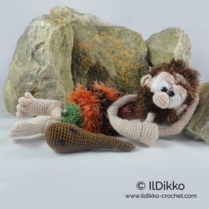 May include: A crocheted caveman doll with beige skin, a dark brown fuzzy mane, and a textured orange and black garment. The doll holds a brown crocheted club and features black bead eyes. Text at the bottom reads: &copy; ILDikko www.ildikko-crochet.com