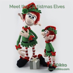 May include: Two crocheted elf dolls with red hair, green outfits, and red and white striped legs. The taller elf stands with a hand on its chest, while the smaller one stands beside it. A small gift box sits between them. Text reads: Meet the Chrtistmas Elves.
