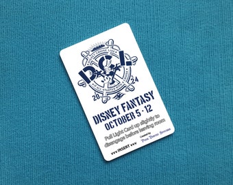 Könnte beinhalten: Eine weiße Karte mit einem blauen Disney Cruise Line-Logo, das Mickey Mouse zeigt. Der Text lautet "Disney Fantasy October 5-12". Die Karte enthält auch die Anweisungen "Pull Light Card up slightly to disengage before leaving room".