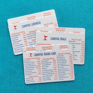May include: Three white rectangular plastic cards featuring printed cruise ship deck plans for Carnival Luminosa, Carnival Magic, and Carnival Mardi Gras. Each card displays lists of dining options, bars, lounges, and entertainment venues with red and blue text.