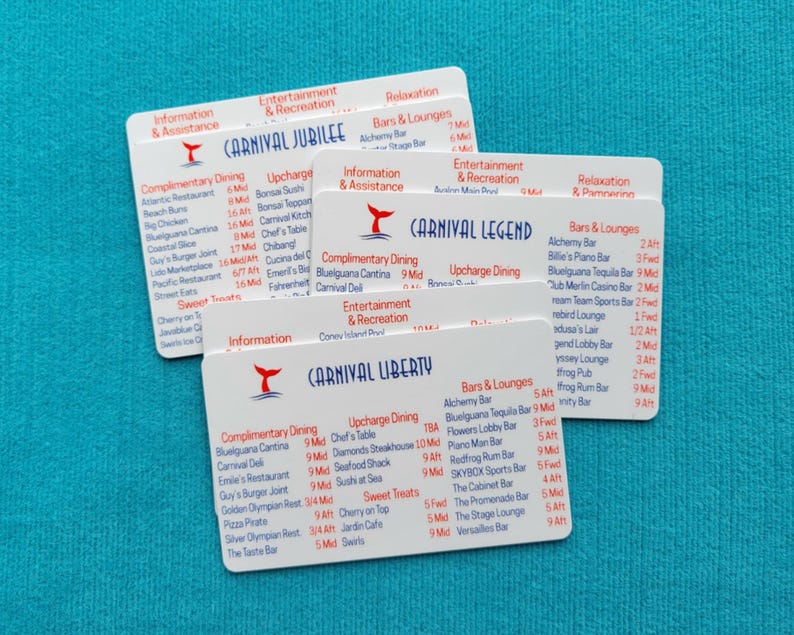 May include: Three white rectangular plastic cards featuring printed deck plans and venue lists for Carnival Jubilee, Carnival Legend, and Carnival Liberty cruise ships. Each card displays red headers and blue text detailing dining, bars, and entertainment.