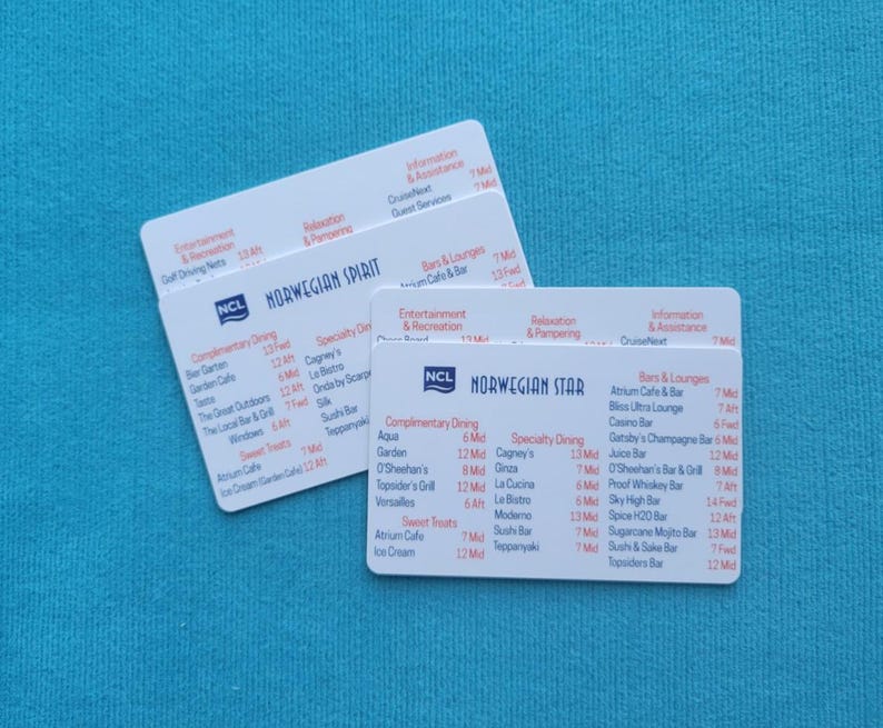 May include: Two white cards with the NCL logo and the words "Norwegian Spirit" and "Norwegian Star" printed on them. The cards list complimentary dining options, specialty dining options, bars and lounges, entertainment and recreation, relaxation and pampering, information and assistance, and guest services.
