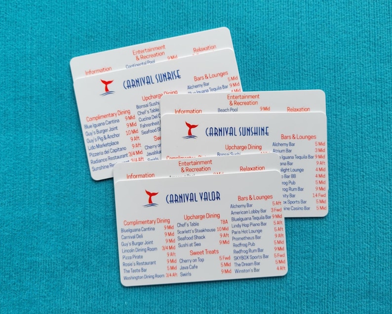 May include: Three white rectangular plastic cards featuring the Carnival cruise ship logos and names Carnival Sunrise, Carnival Sunshine, and Carnival Valor, with printed lists of dining, entertainment, and bar locations on each card.