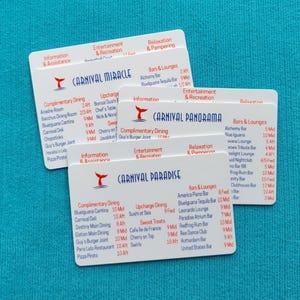 May include: Three white rectangular plastic cards featuring cruise ship deck plans for Carnival Miracle, Carnival Panorama, and Carnival Paradise. Each card displays red and blue text listing dining, entertainment, and lounge locations with deck numbers.