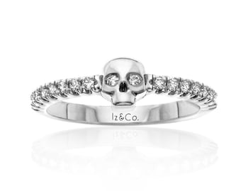 May include: A silver ring with a skull design and a band of small diamonds. The ring is engraved with the text "Iz&Co."