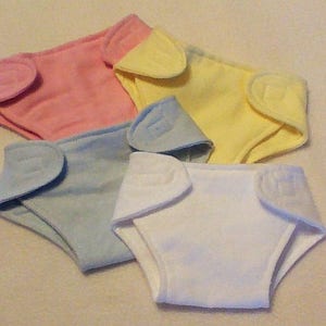 May include: Four cloth baby diapers in pink, light blue, yellow, and white.
