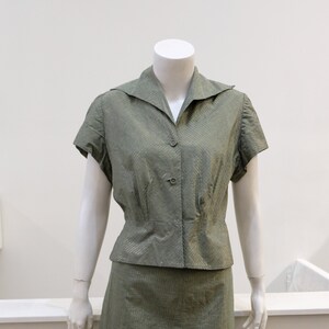 May include: A green, striped, two-piece outfit with a collared, short-sleeved blouse and a skirt.