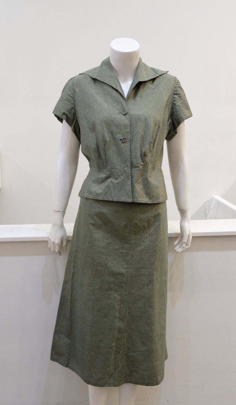 May include: A green, striped, two-piece outfit with a collared, short-sleeved blouse and a skirt.