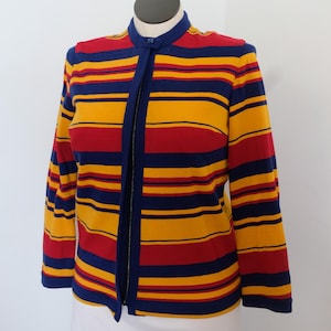 May include: A long-sleeved, striped jacket in red, yellow, and navy blue. The jacket has a stand-up collar and a full-length zipper. The stripes are horizontal and evenly spaced. The jacket is displayed on a mannequin.