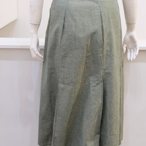May include: A green skirt with a subtle gold stripe pattern. The skirt has a straight silhouette and a slightly flared hem.