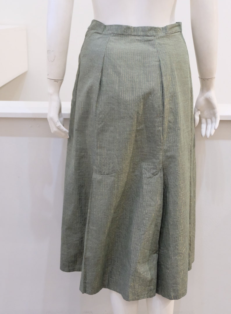 May include: A green skirt with a subtle gold stripe pattern. The skirt has a straight silhouette and a slightly flared hem.