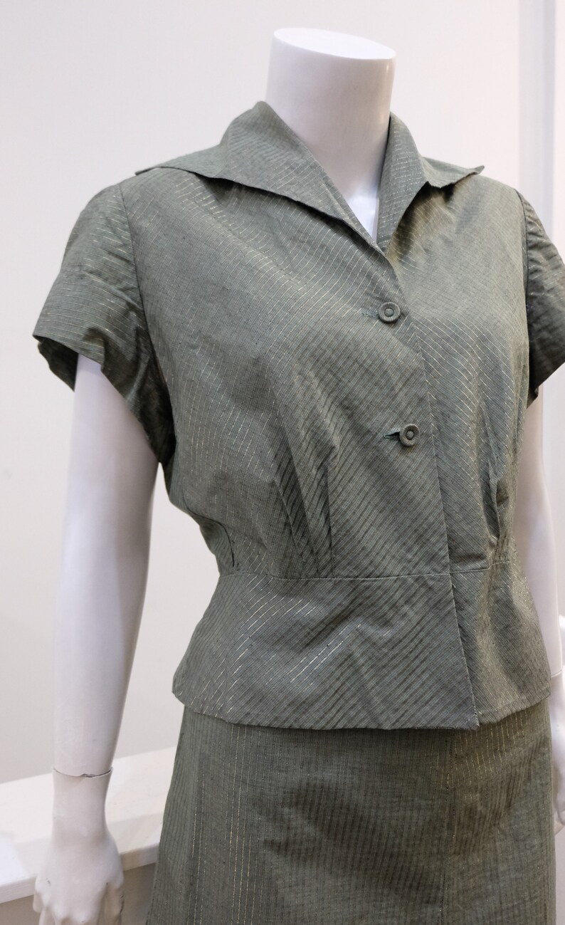 May include: A green and gold striped short-sleeved blouse and skirt set. The blouse has a collared neckline and a button closure. The skirt is a-line and has a high waist.