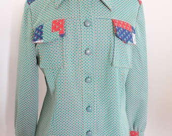 May include: A vintage green button-down shirt with a small square pattern. The shirt features patch pockets and cuffs with red, white, and blue patterned accents. The shirt is displayed on a mannequin.