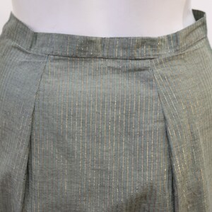 May include: A green skirt with thin gold stripes. The skirt has a waistband and a pleated front.