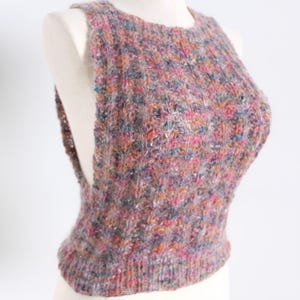 May include: A sleeveless, multi-colored knit top with a round neckline. The top is displayed on a mannequin and features a textured, speckled pattern with hues of pink, purple, orange, and teal. The garment has a ribbed hem.