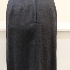 May include: A black skirt with a zipper closure in the back. The skirt is made of a textured fabric.