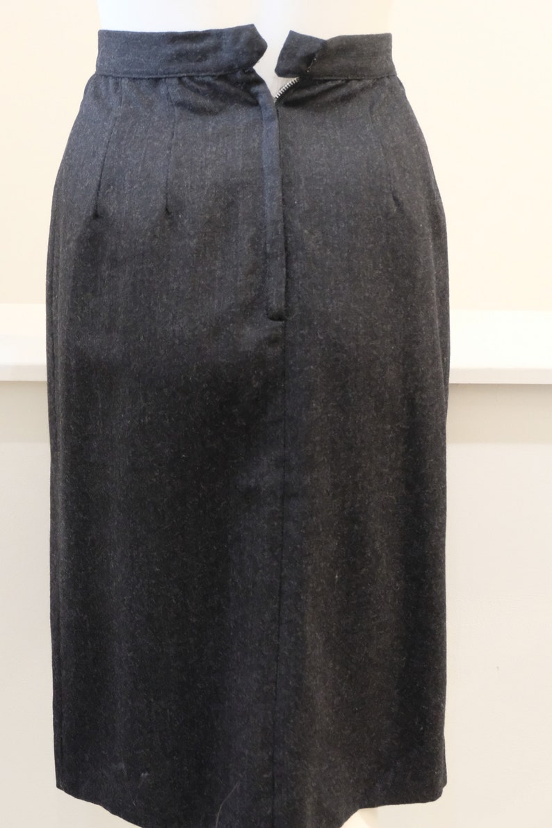 May include: A black skirt with a zipper closure in the back. The skirt is made of a textured fabric.