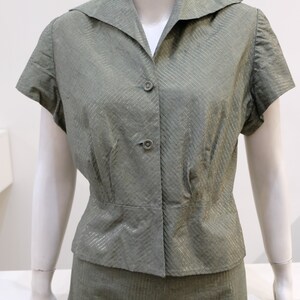 May include: A green and silver striped short-sleeved blouse and skirt set. The blouse has a collared neckline and button closure. The skirt is a-line and has a waistband.