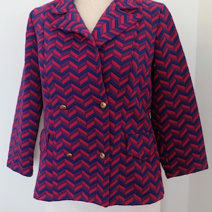 May include: A double-breasted blazer in a vibrant chevron pattern of red and blue. The jacket features gold-colored buttons and two front pockets. The blazer is displayed on a mannequin.