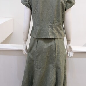 May include: A green and gold striped skirt and matching short-sleeved blouse. The skirt is knee-length and has a slight A-line shape.
