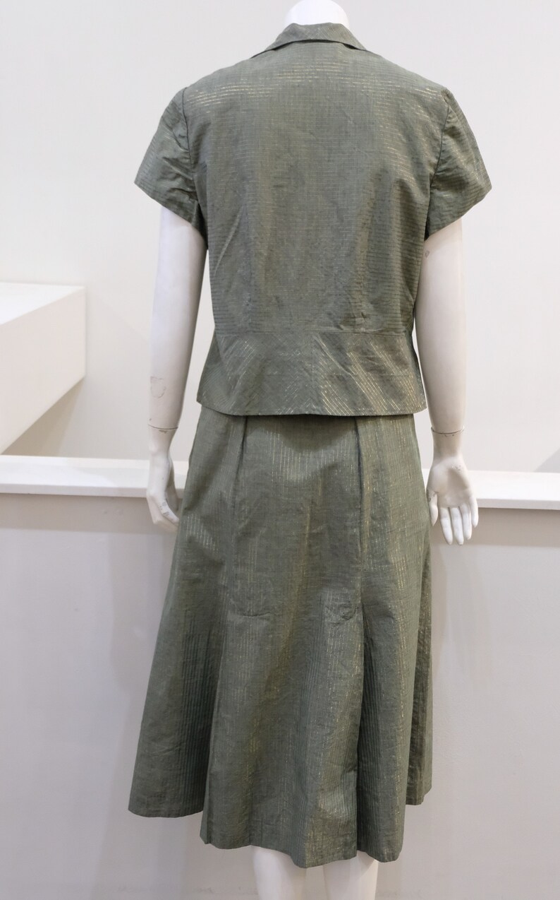 May include: A green and gold striped skirt and matching short-sleeved blouse. The skirt is knee-length and has a slight A-line shape.
