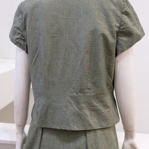 May include: A green and gold striped short-sleeved blouse and skirt set. The fabric has a subtle sheen.