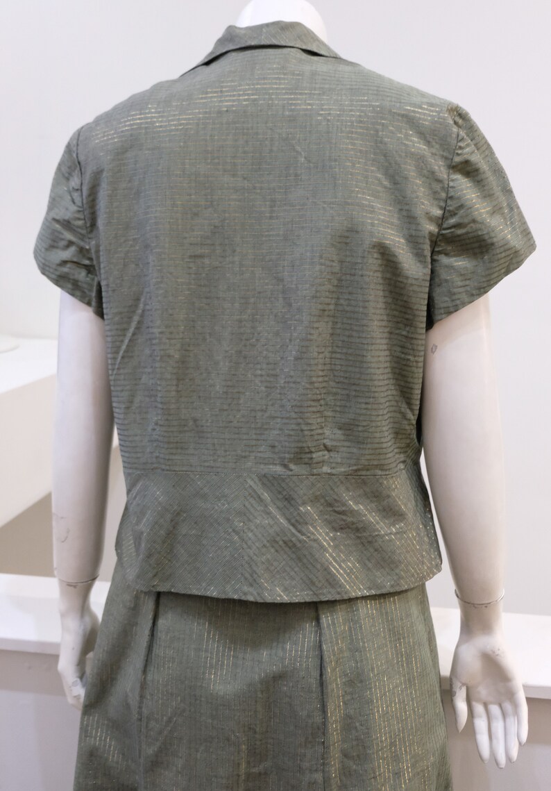 May include: A green and gold striped short-sleeved blouse and skirt set. The fabric has a subtle sheen.