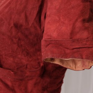 K&ouml;nnte beinhalten: Nahaufnahme einer rostfarbenen Jacke mit umgeschlagenem &Auml;rmel. Die Jacke hat eine Tasche und Kn&ouml;pfe vorne. Die Innenseite des &Auml;rmels ist hellbraun.