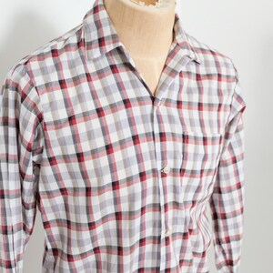 May include: A long-sleeved, button-down shirt with a plaid pattern in red, black, and white. The shirt is displayed on a mannequin and features a chest pocket and a classic collar.