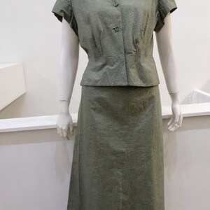 May include: A green, short-sleeved blouse with a collar and a matching skirt. The fabric has a subtle shimmer.