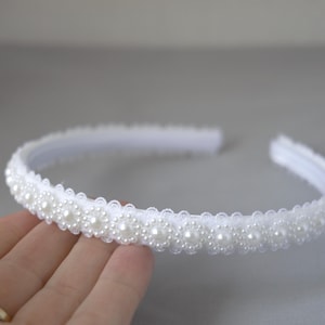 May include: A white headband with a row of pearl-like beads.