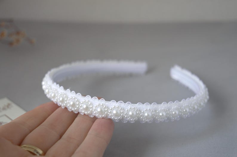 May include: A white headband with a row of pearl-like beads.