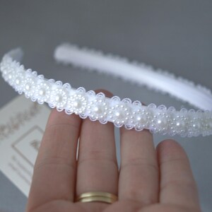 May include: A white headband with a row of pearl-like embellishments.