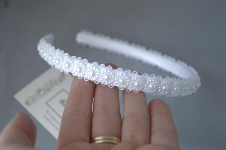May include: A white headband with a row of pearl-like embellishments.