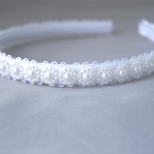 May include: A white headband with a row of pearl-like beads.