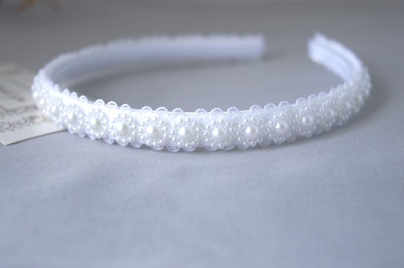 May include: A white headband with a row of pearl-like beads.