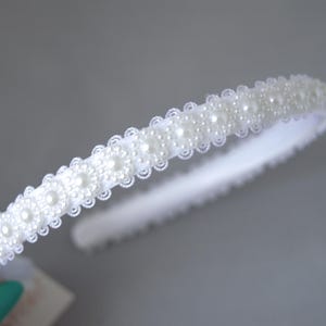 May include: A white headband with a row of faux pearls.