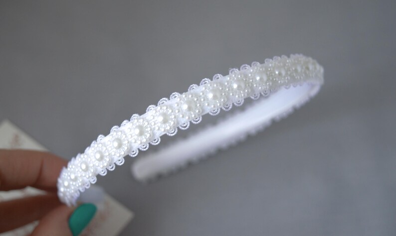 May include: A white headband with a row of faux pearls.