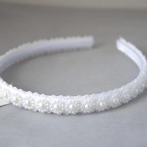 May include: A white headband with a row of white pearl beads.