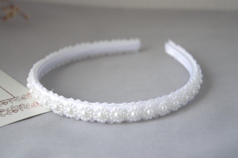 May include: A white headband with a row of white pearl beads.