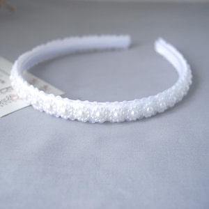 May include: A white headband with a row of white pearl-like beads.