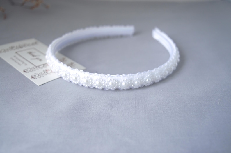 May include: A white headband with a row of white pearl-like beads.