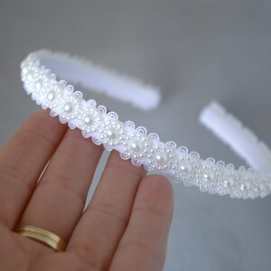 May include: White headband with a row of pearl-like embellishments.